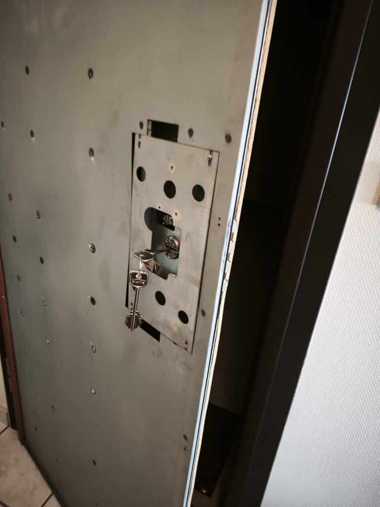 Clé Dierre insérée dans le mécanisme interne d'une porte blindée en cours de réparation.